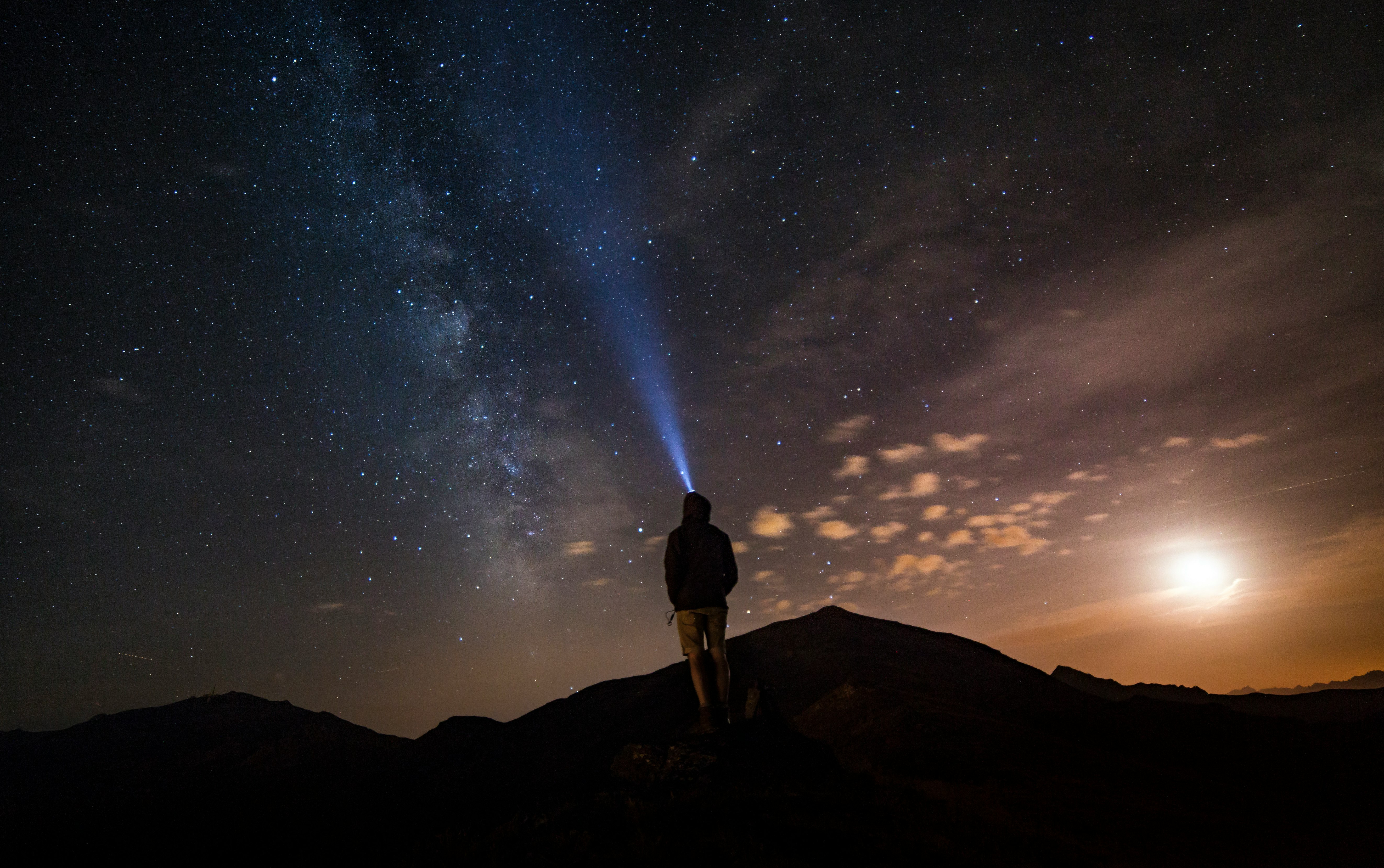 man standing at mountain peak under starry night sky